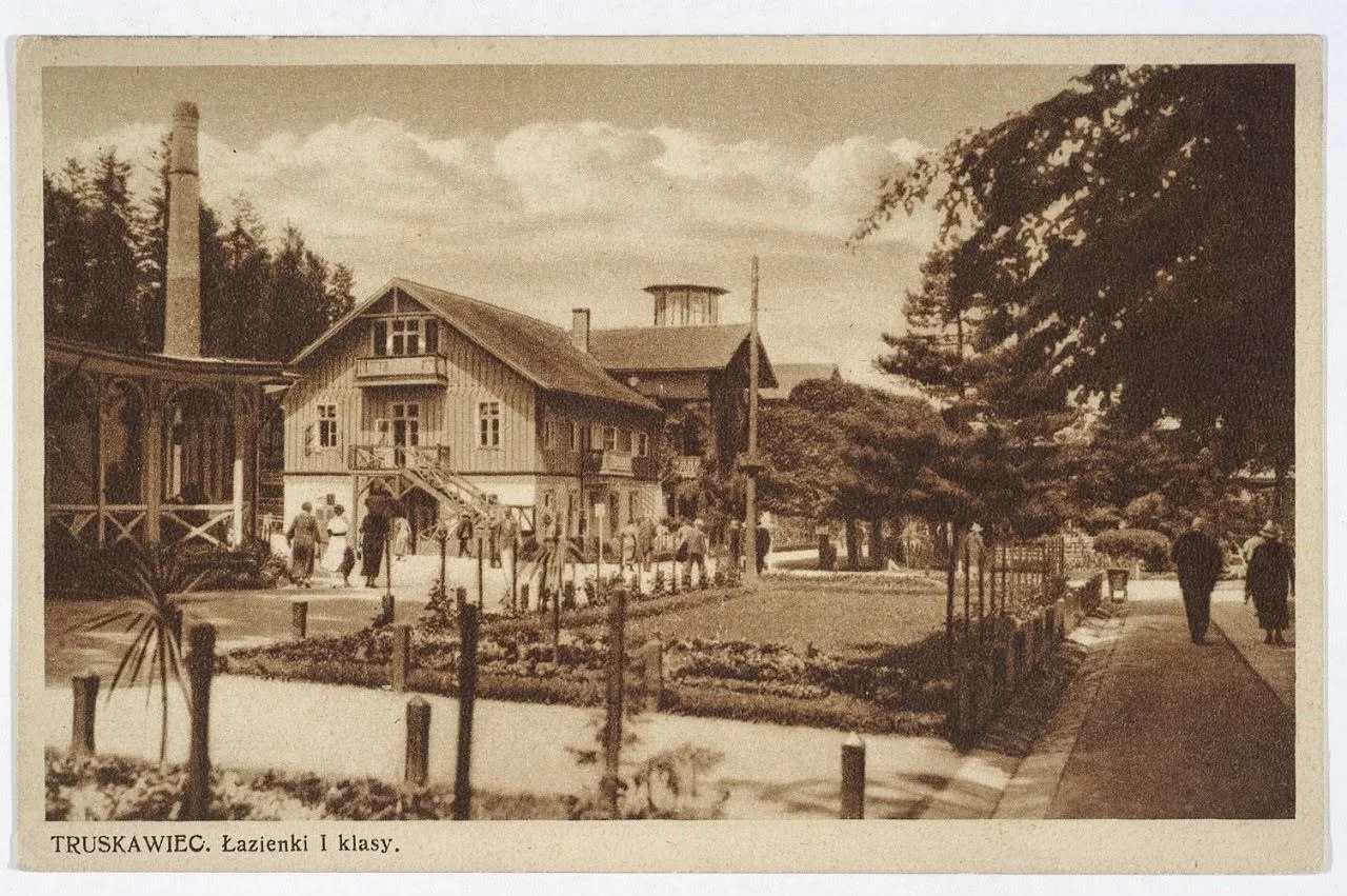 Дерев'яна водолікарня «Лазєнки I класу» в Трускавці на листівці 1920–1930-х: будинок із вежею, цегляний димар і квітник перед ним