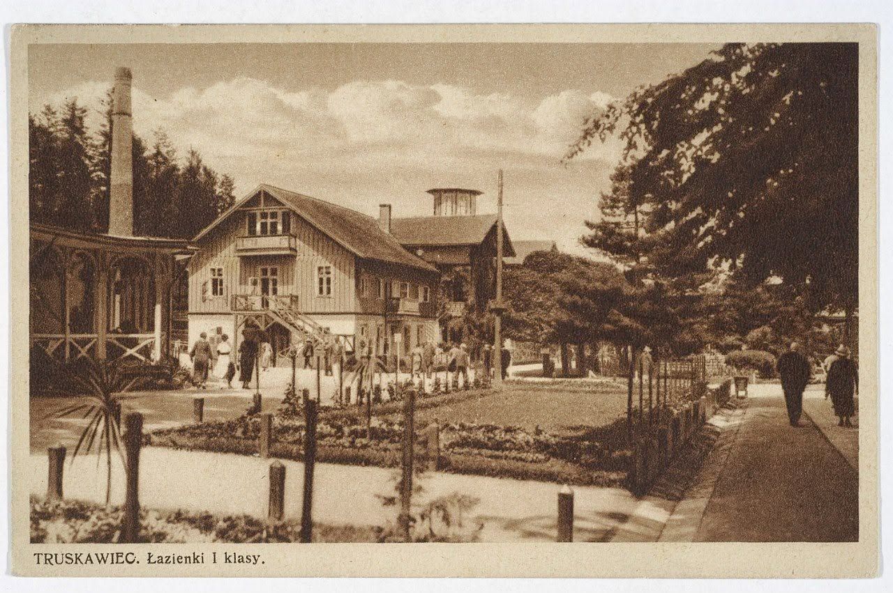 Дерев'яна водолікарня «Лазєнки I класу» в Трускавці на листівці 1920–1930-х: будинок із вежею, цегляний димар і квітник перед ним