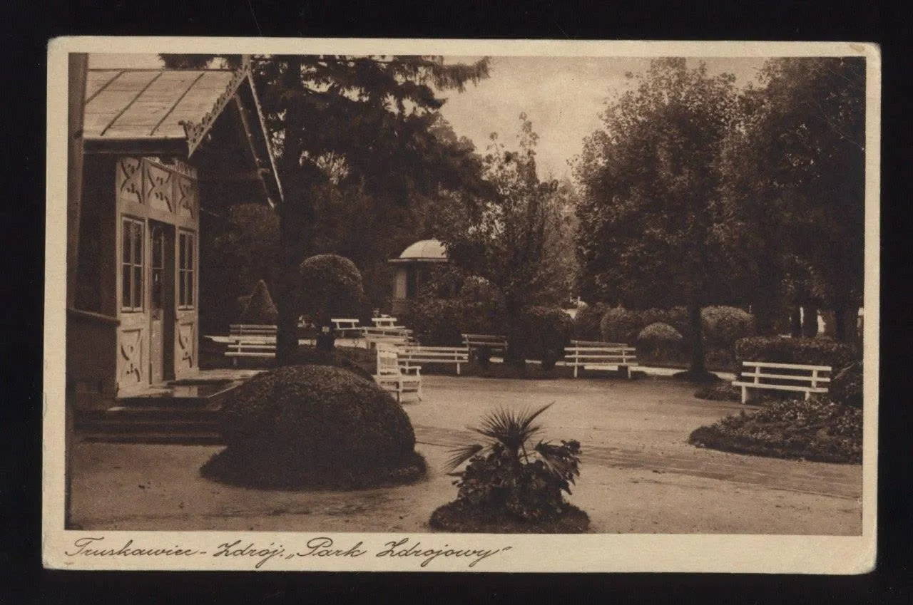 Куточок курортного парку Трускавця на листівці 1920-х: різьблений дерев'яний павільйон, білі лави, стрижені кущі