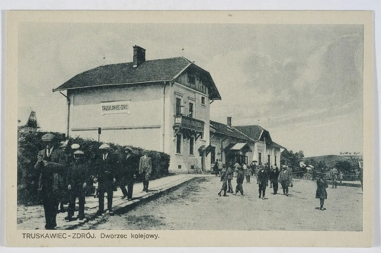 Залізничний вокзал Трускавця на листівці 1920–1930-х: двоповерхова будівля з написом «TRUSKAWIEC-ZDRÓJ» на фронтоні та люди на майдані
