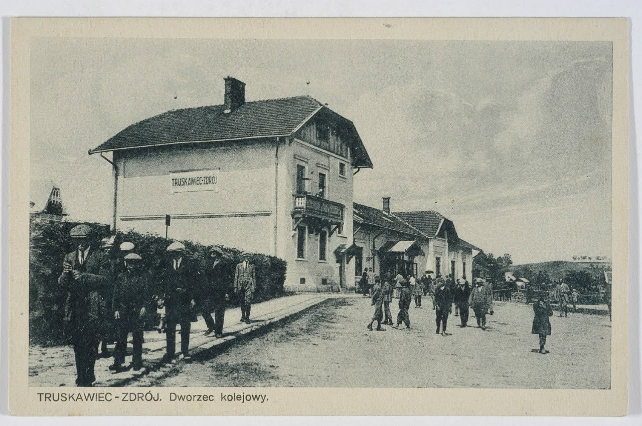 Залізничний вокзал Трускавця на листівці 1920–1930-х: двоповерхова будівля з написом «TRUSKAWIEC-ZDRÓJ» на фронтоні та люди на майдані